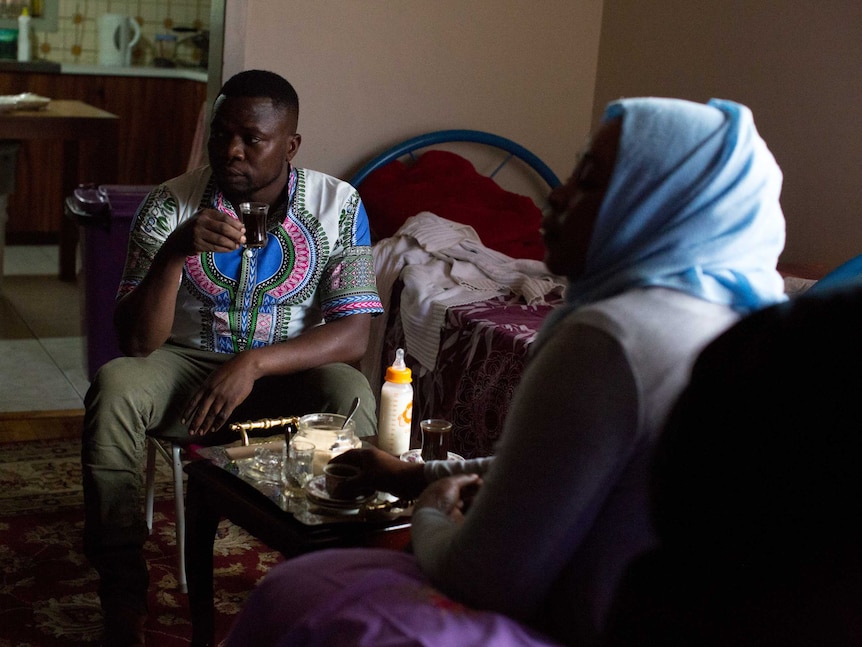 Elssaied and Kadiga sip coffee in their living room