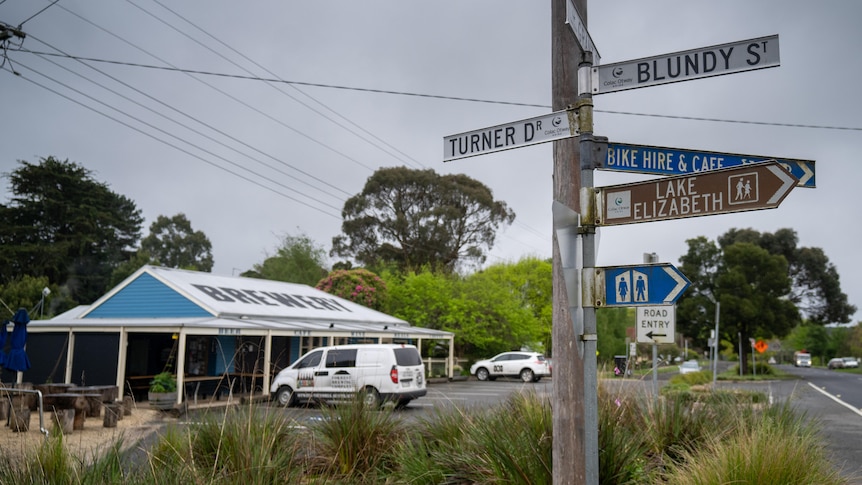 A street scene with a signpost in the foreground.