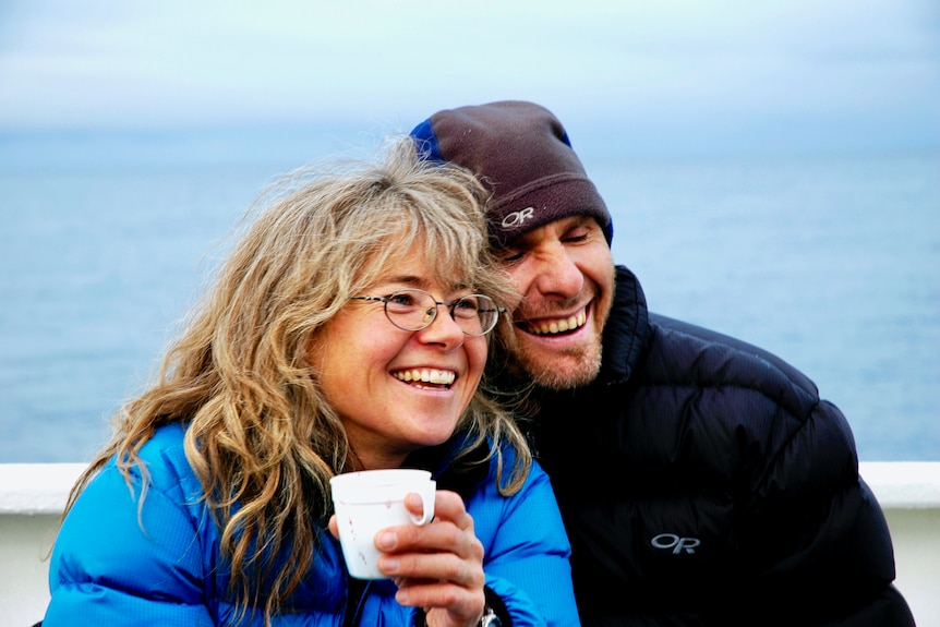 Middle aged couple hug side-by-side outdoors in winter time