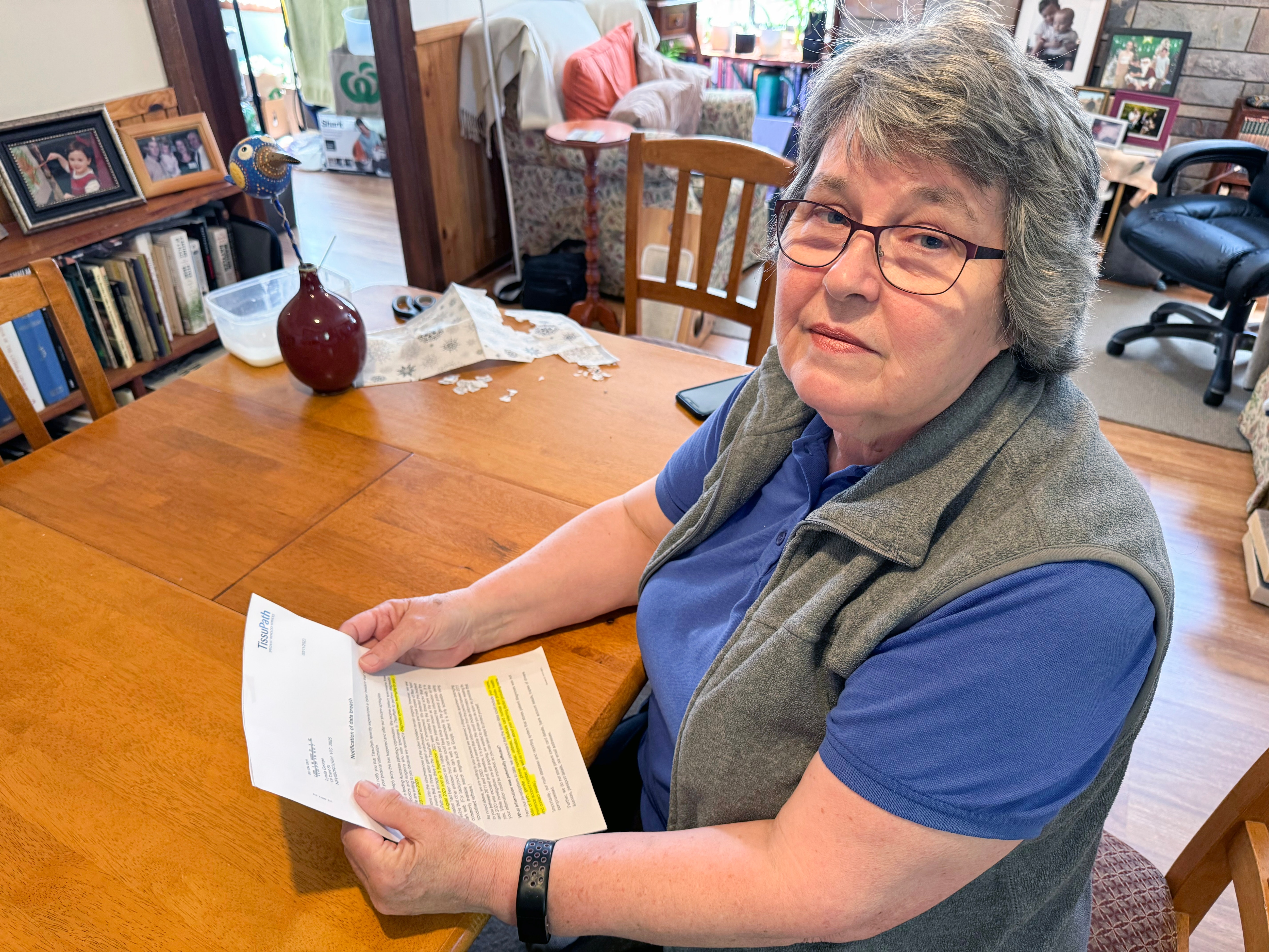 Lynda George holds a letter and looks at the camera