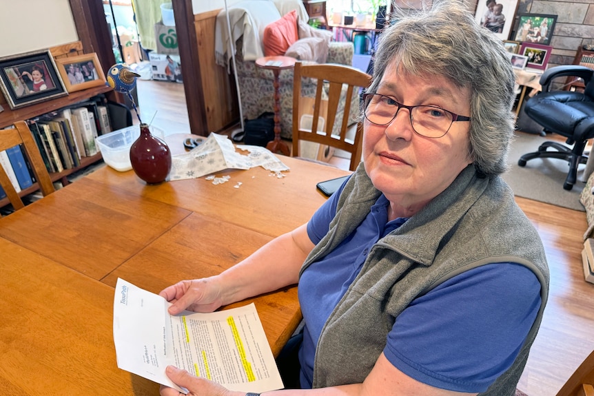 Lynda George holds a letter and looks at the camera