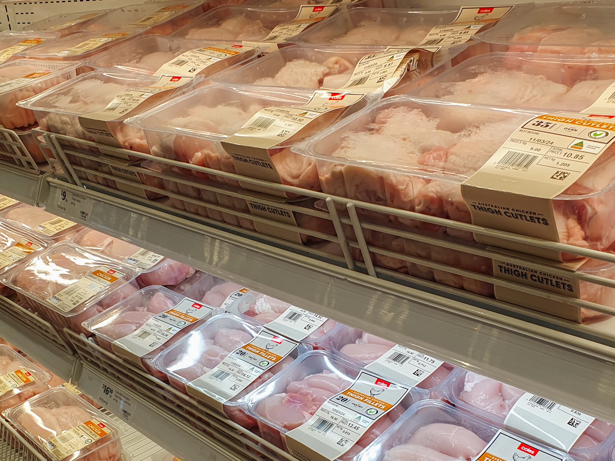 Grocery store racks with packages of processed chicken meat. 