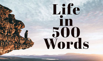 A person on a rocky out crop looking at a sunrise with words "Life in 500 Words" over the clouds