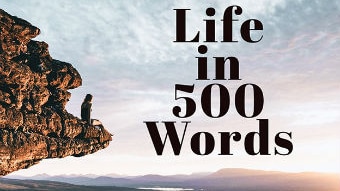 A person on a rocky out crop looking at a sunrise with words "Life in 500 Words" over the clouds