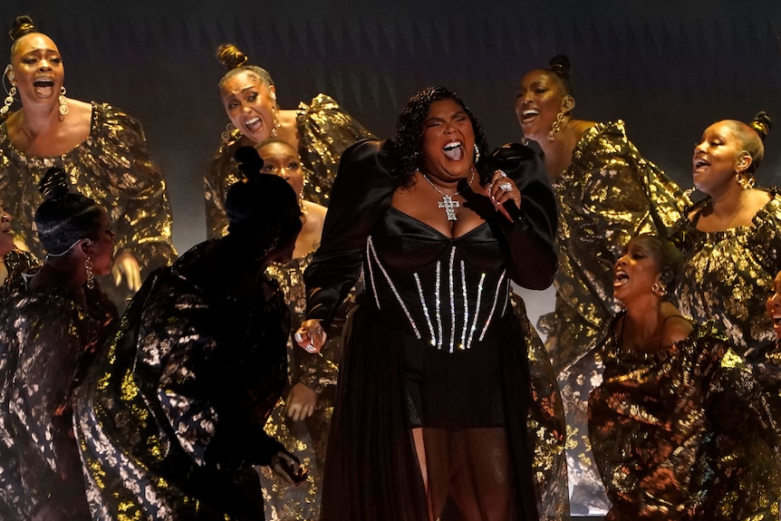 Lizzo screams into a microphone, surrounded by back-up singers, onstage at the Grammys.