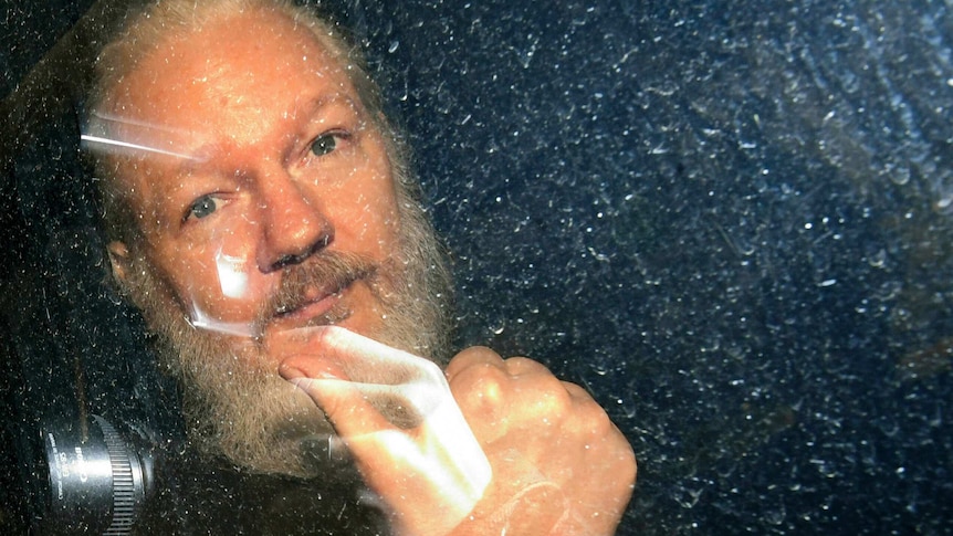 Julian Assange gestures as he arrives at Westminster Magistrates' Court in London.