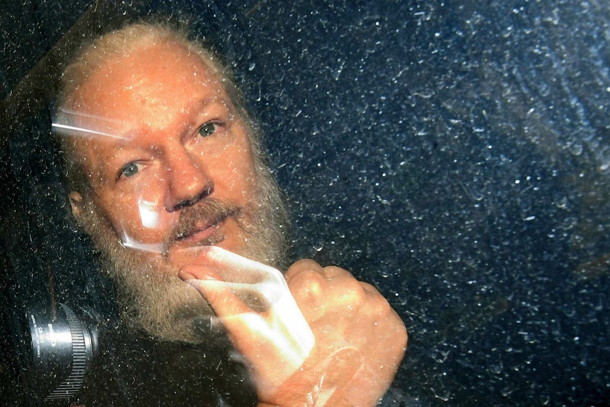 Julian Assange gestures as he arrives at Westminster Magistrates' Court in London.