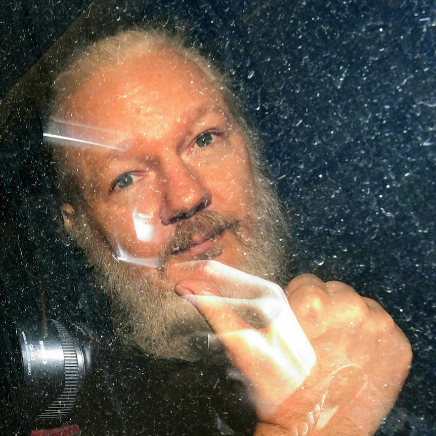 Julian Assange gestures as he arrives at Westminster Magistrates' Court in London.