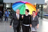 Andrew Wilkie, Felicity Marlowe and Sarah Marlowe (left to right) leave the High Court under a rainbow umbrella.