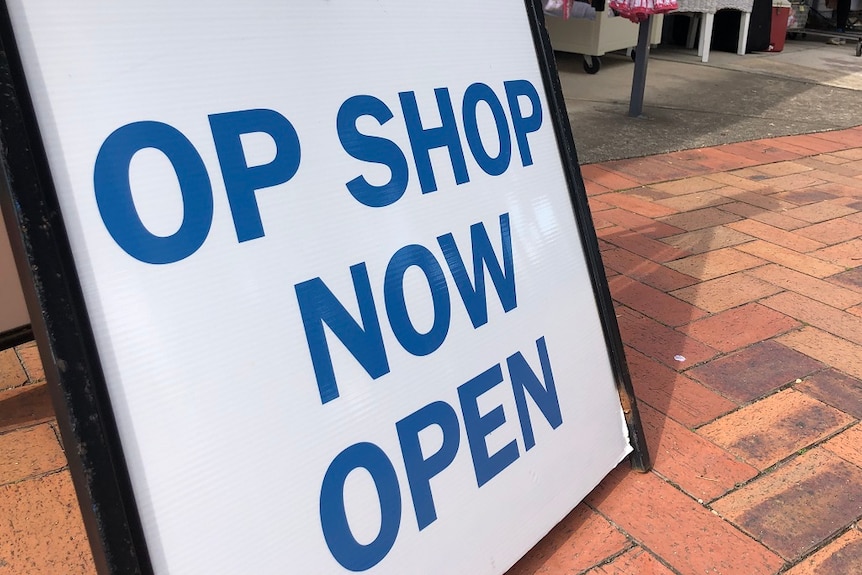 A sandwich board sign that reads op shop now open