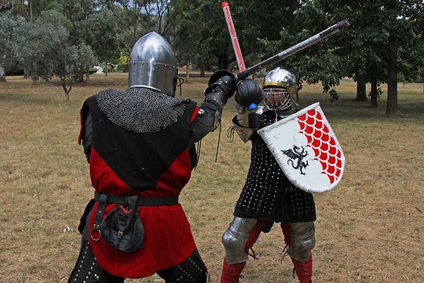 Two people dressed in heavy armour fighting with Rotan swords.