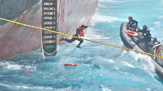 A crew member jumps from a phosphate ship