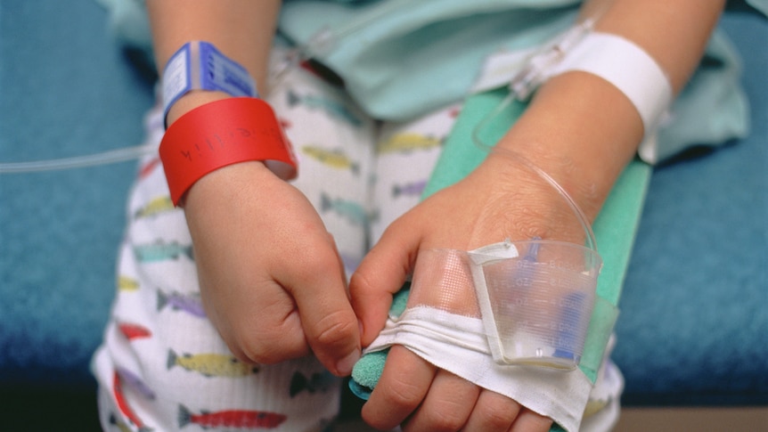 Young boy in hospital bed showing intravenous lines in arm.