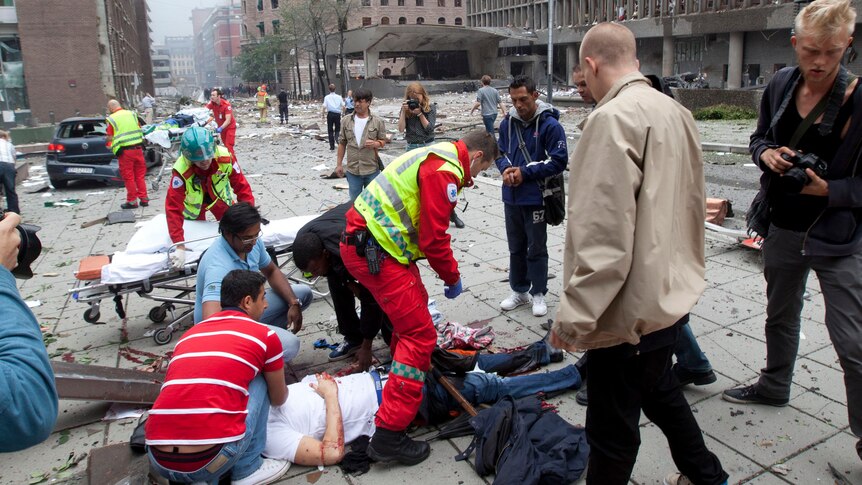 Rescue officials tend to a wounded man after a powerful explosion rocked central Oslo