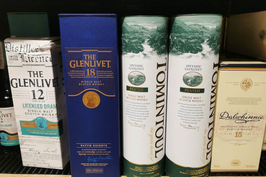 Tall boxes containing several brands of scotch whisky sit on a shelf