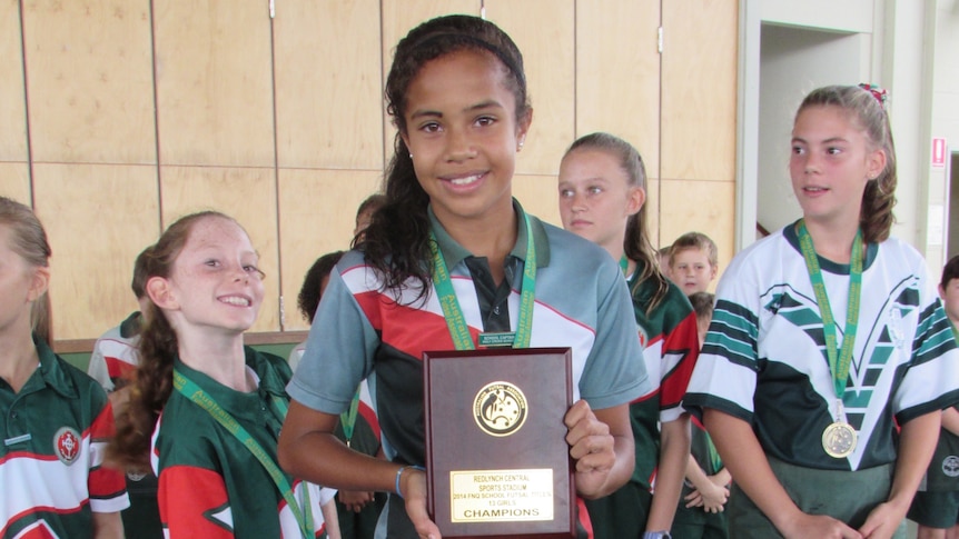 Schoolgirl holding a trophy.