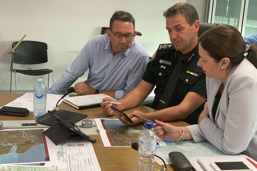 Craig Crawford in a meeting with Premier Annastacia Palaszczuk sitting at desk looking at papers.