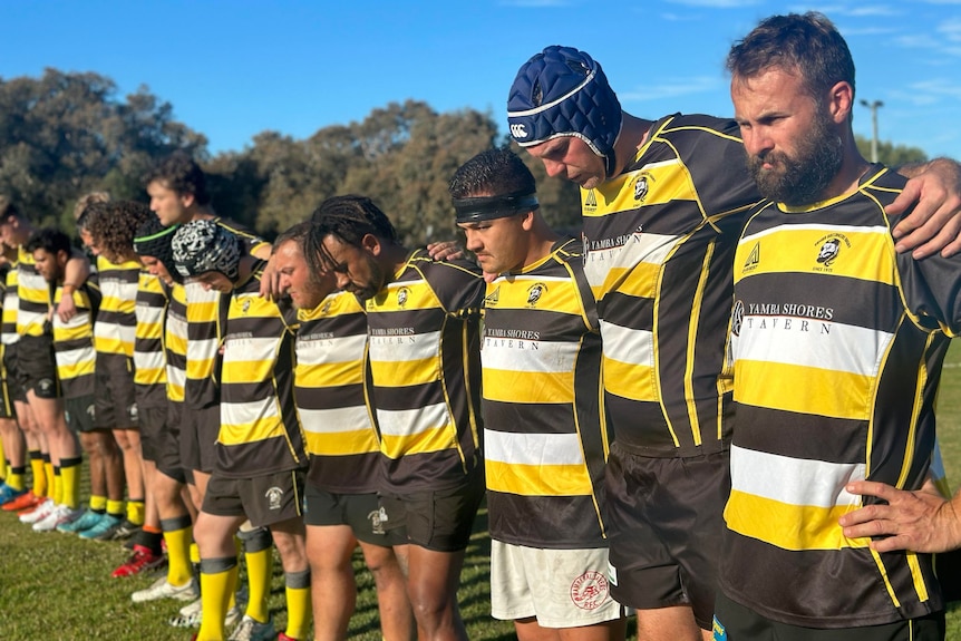 Rugby players stay silent in a row before a match. 