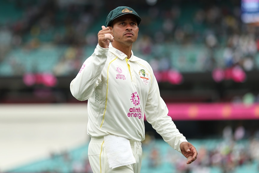 Usman Khawaja walks off the SCG wearing his baggy green cap and gives a thumbs up to the crowd. 