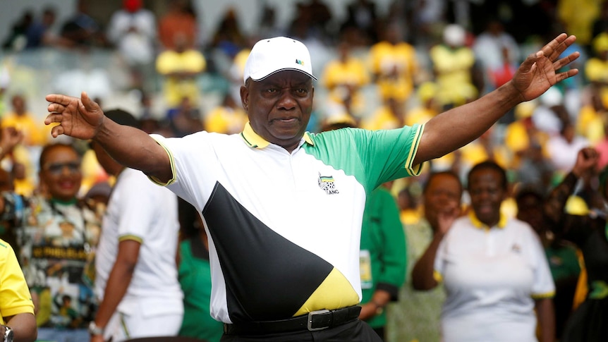 Cyril Ramaphosa with arms spread wide amid crowd of people.