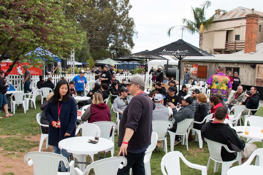 People sitting on plastic chairs and tables at a pub beer garden.