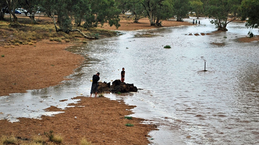 Children play in the swollen Todd River as water floods the normally dry river bed