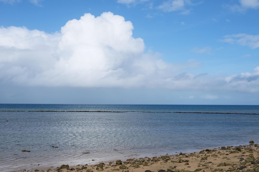 The sea with a line of rocks dotted in the water.