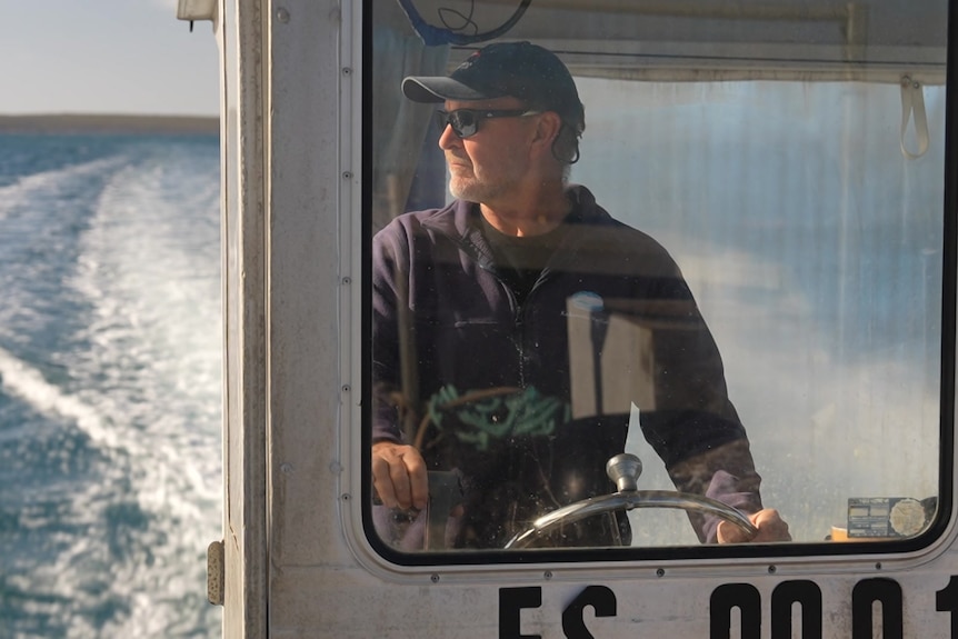 A man looks out as he drives a boat at sea