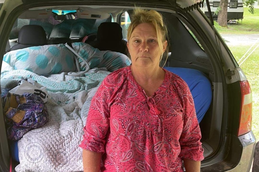 Vicki sits at back of her car.