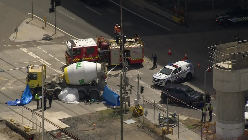 Emergency services vehicles surround a cement mixer involved in a fatal accident with a cyclist