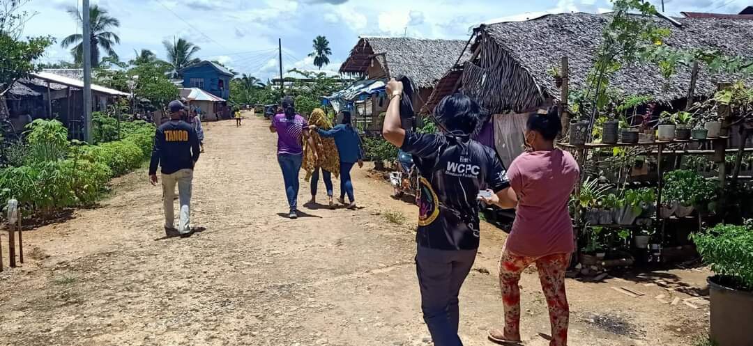People walking through a village on a dirt road