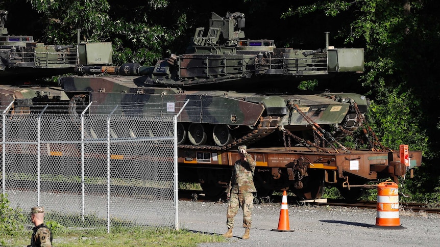 Military walk near tanks on a flat car in Washington