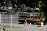 Military walk near tanks on a flat car in Washington