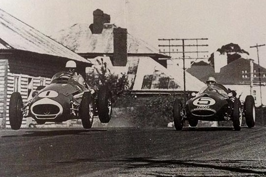 A historic shot of a racing car in action on a circuit in a town.
