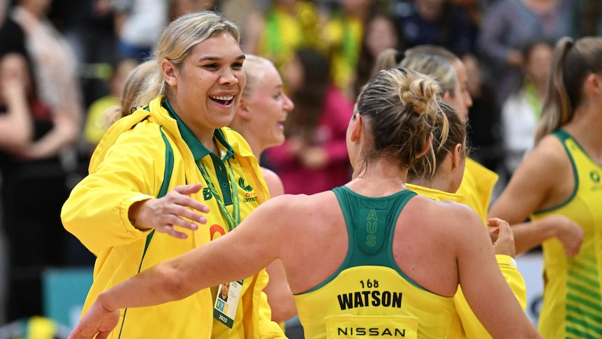Donnell Wallam wears her Diamonds green and gold tracksuit as she hugs Liz Watson after Game 4