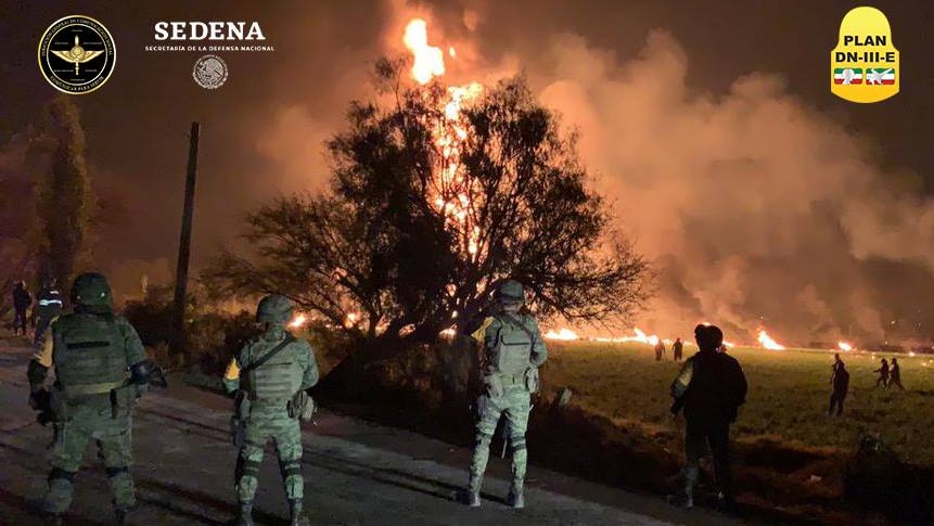 Law enforcement stand guard as a fire burns in a field in central Mexico.