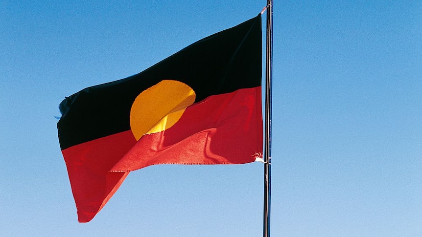 Aboriginal flag (yellow circle on black top half and red bottom half) with blue sky