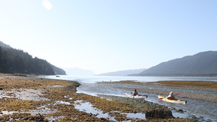The two kayakers departing Juneau, Alaska, flanked by mountains on either side.