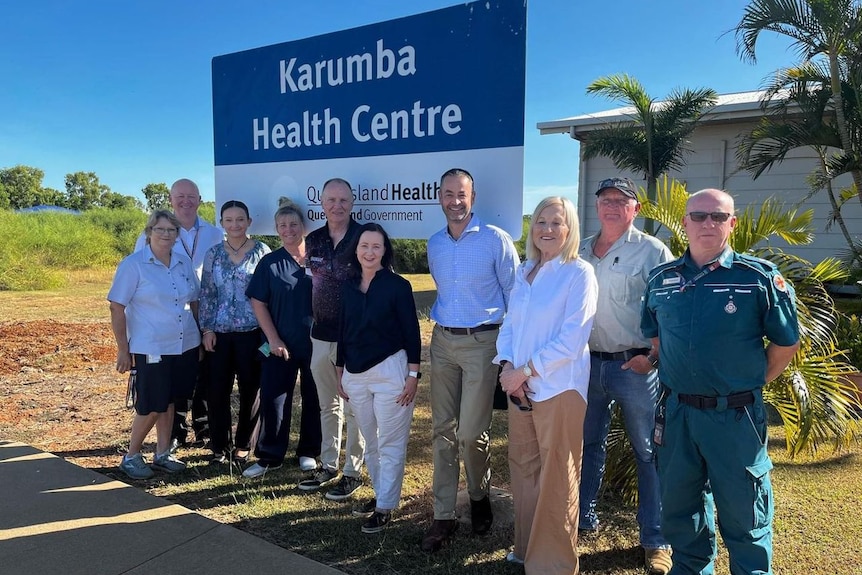 A group of people standing below a sign say Karumba Health Centre.