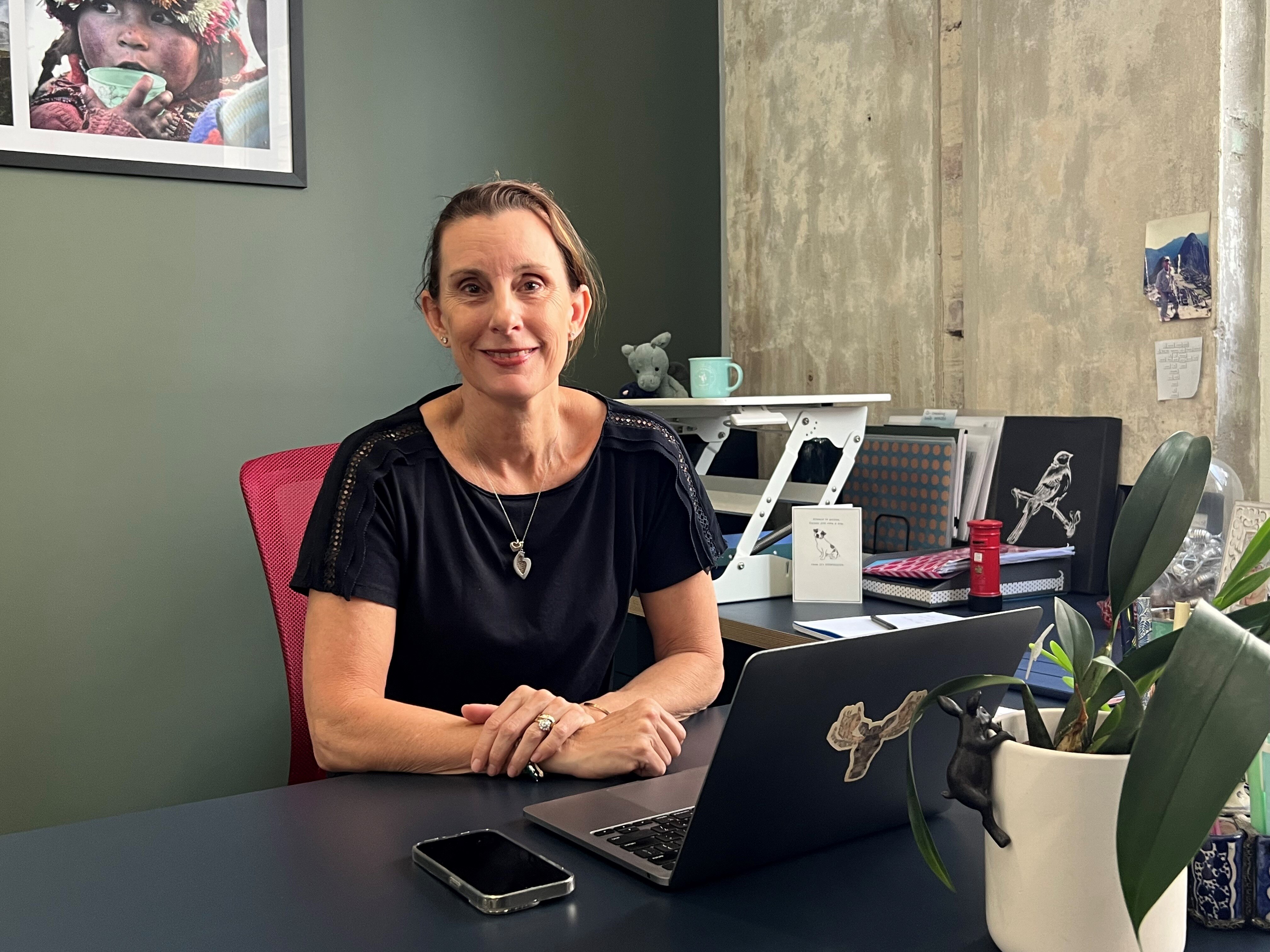 A woman wearing a black top sitting at a desk with a computer