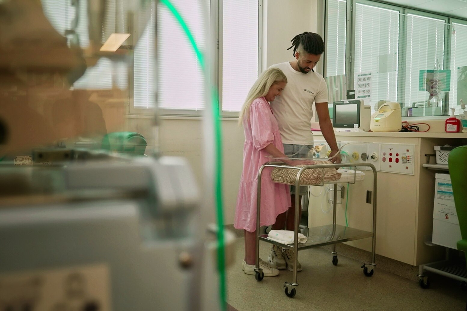 A man and a woman in hospital looking down at their baby boy.