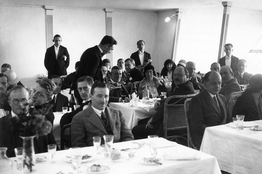 A black and white image of waiters serving guests inside the R101 airship.