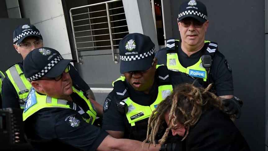 Several police clash with a female demonstrator outside a building.