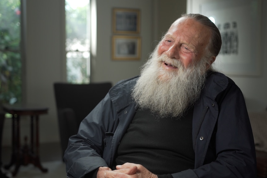 A portrait of actor Jack Thompson in the interview chair, smiling with a big bushy beard