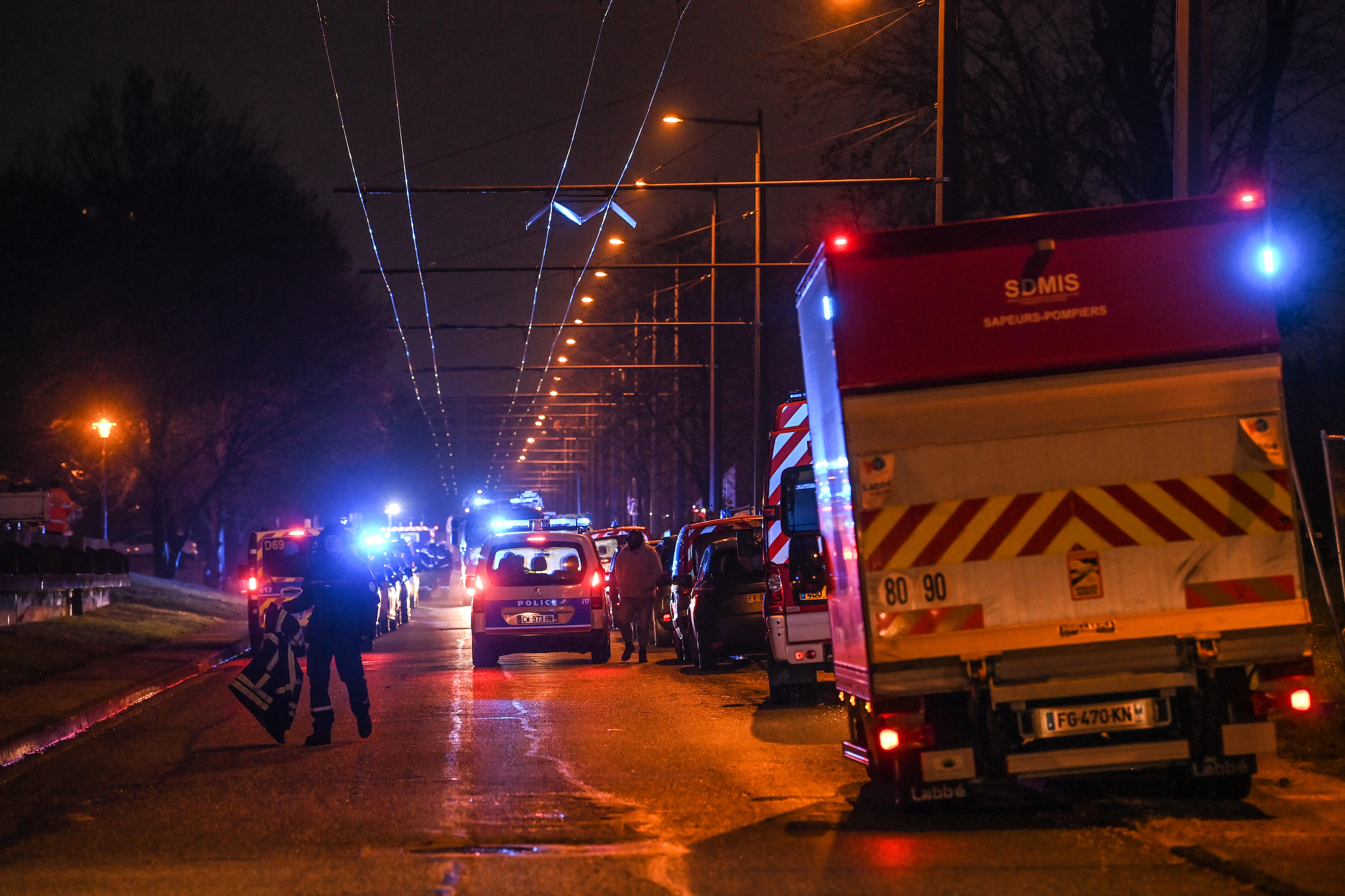 lines of police and emergency services crews line a road in the early morning 