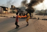 Two children in front of burning tyres