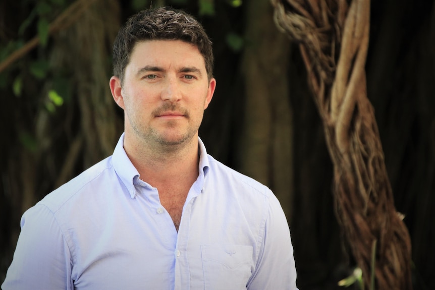 A man stands in front of a tree in the Northern Territory. 