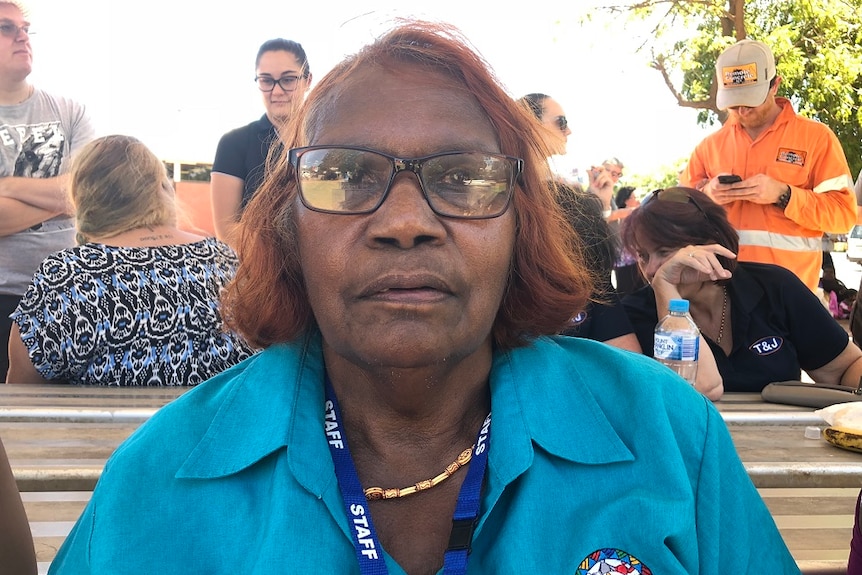 Rosemary Plummer sits with a number of people talking to each other in the background.