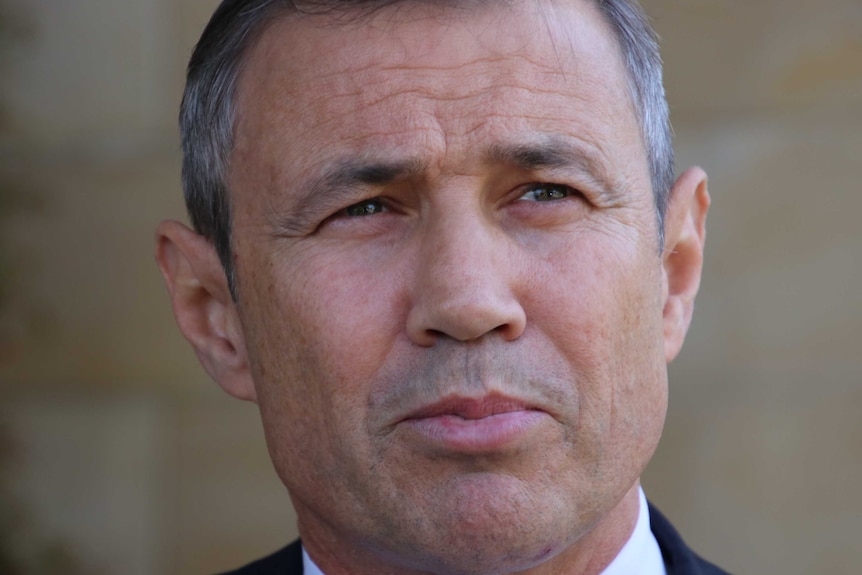 Close up of Roger Cook with his lips together and looking into middle distance.