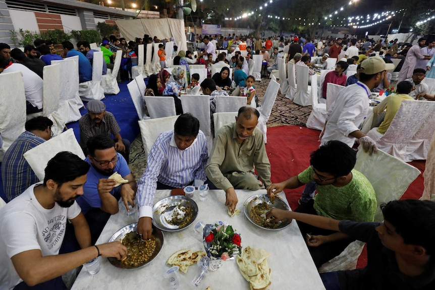 People eat charity food prepared with ostrich meat and chickpea